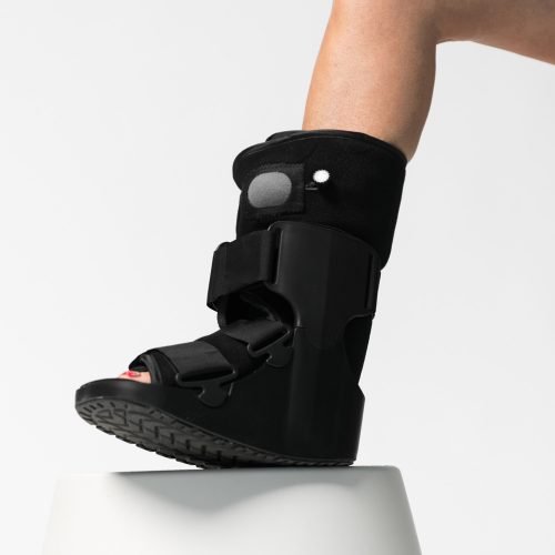 A woman wearing a black AIRFLOWTM BOOT Regular on a stool.