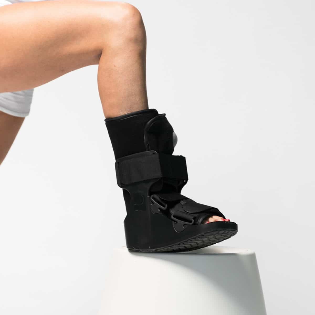 A woman wearing a black AIRFLOWTM BOOT Regular stands on top of a white pedestal.