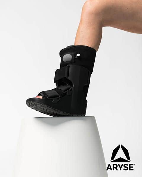 A person standing on a stool with an ankle brace.