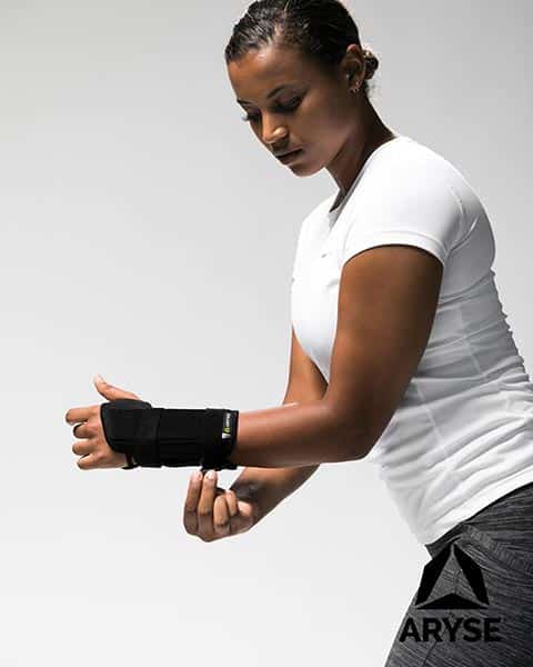 A woman wearing a black wrist brace from ARTIK Medical Supply.