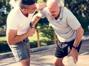 A man is helping an older man with a broken leg.