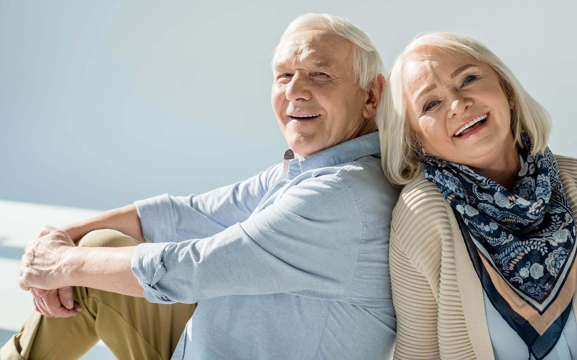 A man and woman sitting back to back, utilizing Artik medical supplies to restore mobility as they check eligibility for insurance coverage.