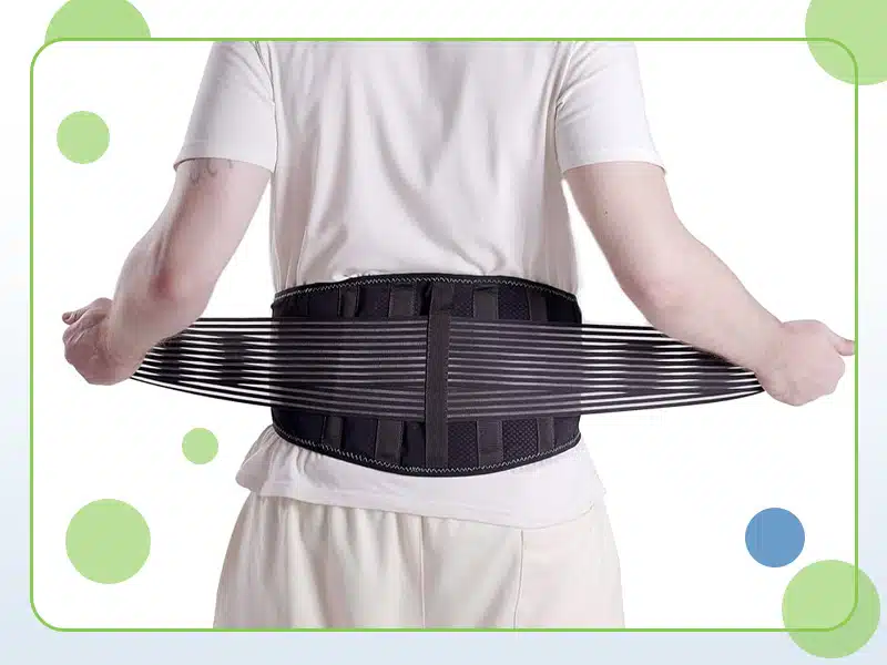 A person wearing a white shirt is seen from the back, adjusting a black lumbar support belt around their waist with outstretched hands, likely seeking back pain relief. Colored circles are present in the background.